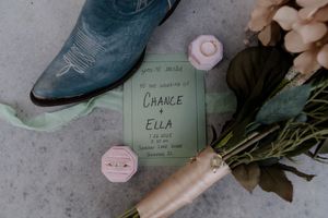 Vintage cowboy boots and pink ring box arranged with handwritten name cards.