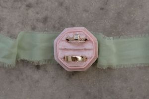 Wedding rings displayed in a pink octagonal box on a mint green ribbon.
