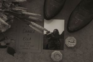 Black and white photo of wedding details including boots and ring box.
