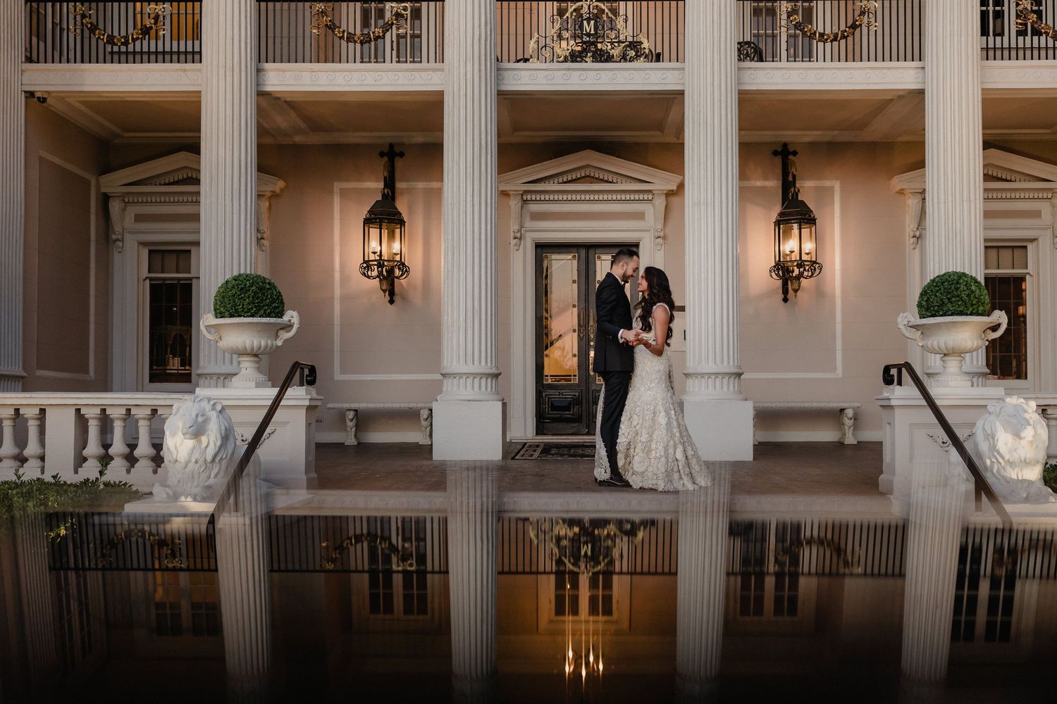 Interior of a grand hall with white columns, ornate balconies, and elegant pendant lighting in classical architecture style.