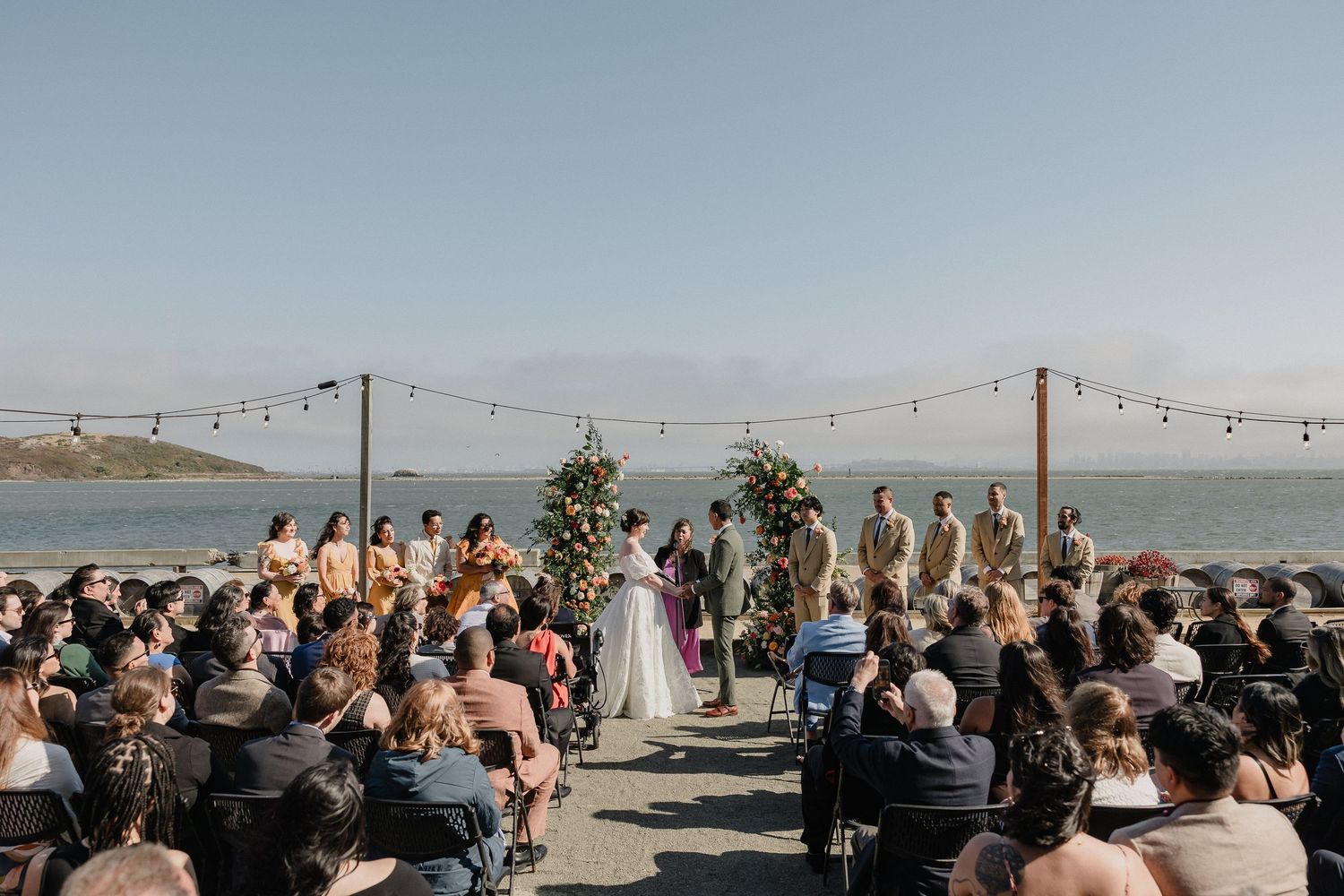 Outdoor wedding ceremony with rows of chairs and a white draping canopy overlooking a scenic desert landscape.