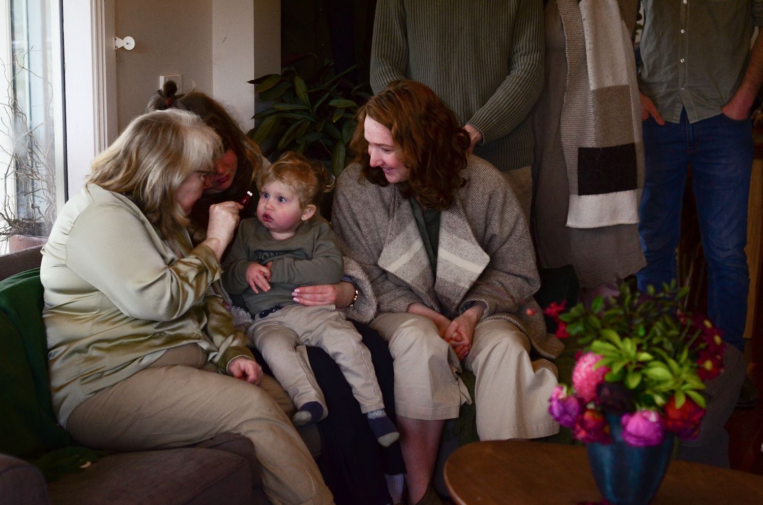 Family relaxing together on a couch while reading books in a cozy living room setting.