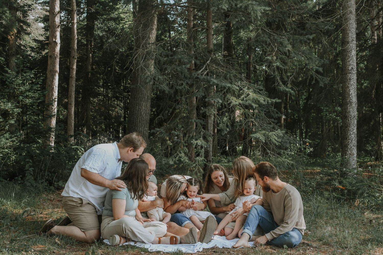 Family gathering on picnic blanket in peaceful forest setting.