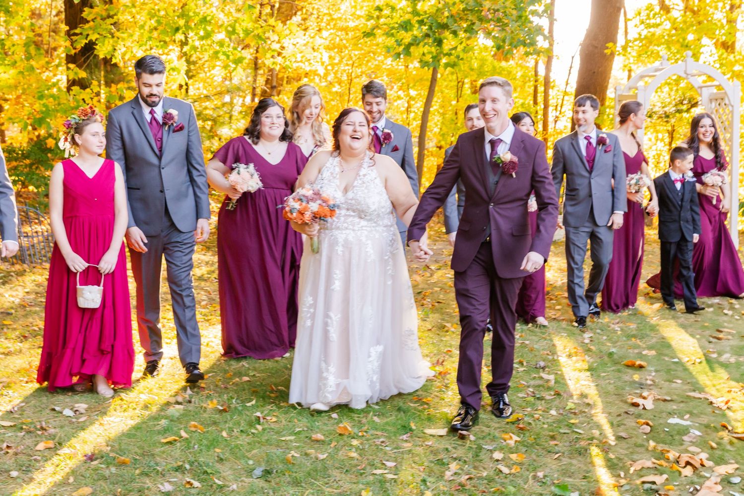 Wedding party celebrates outdoors with burgundy bridesmaids and navy groomsmen.