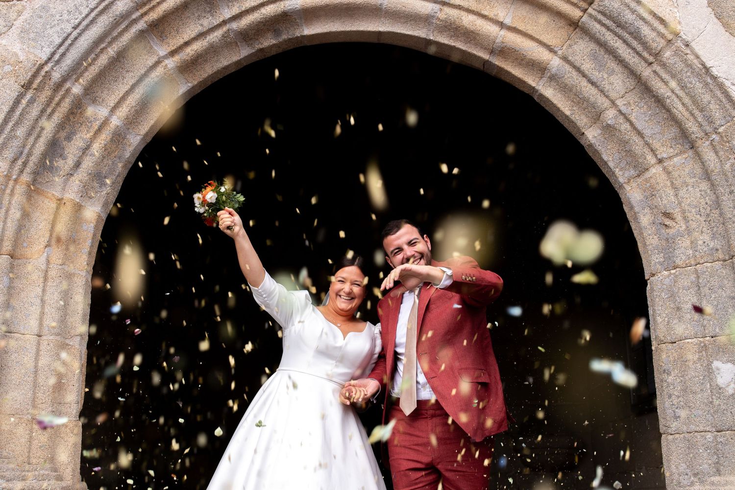 deux mariés à la sortie de l'église heureux avec des pétales de fleurs autour photographie de mariage