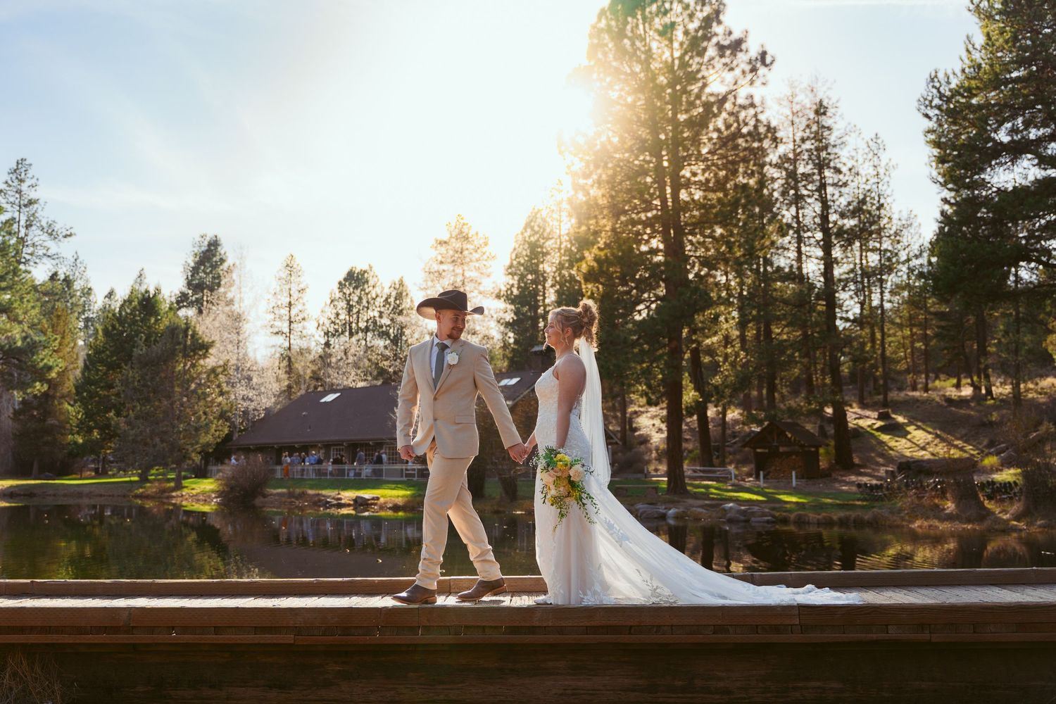 A romantic wedding scene captured in front of a desert mountain landscape with a flowing white veil and bouquet.