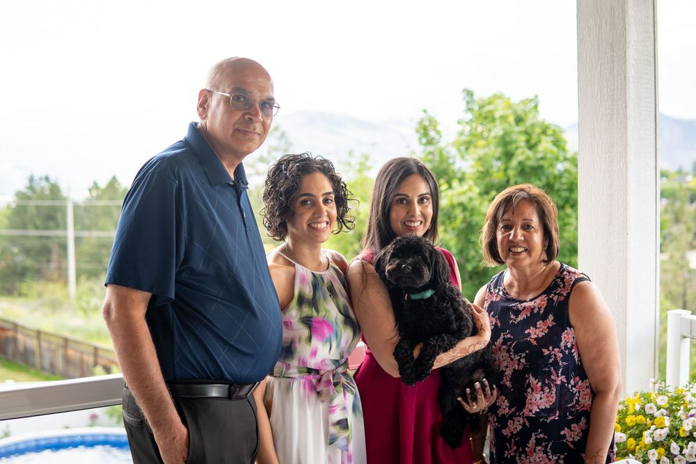 Group gathered on a sunny porch with a small black dog.