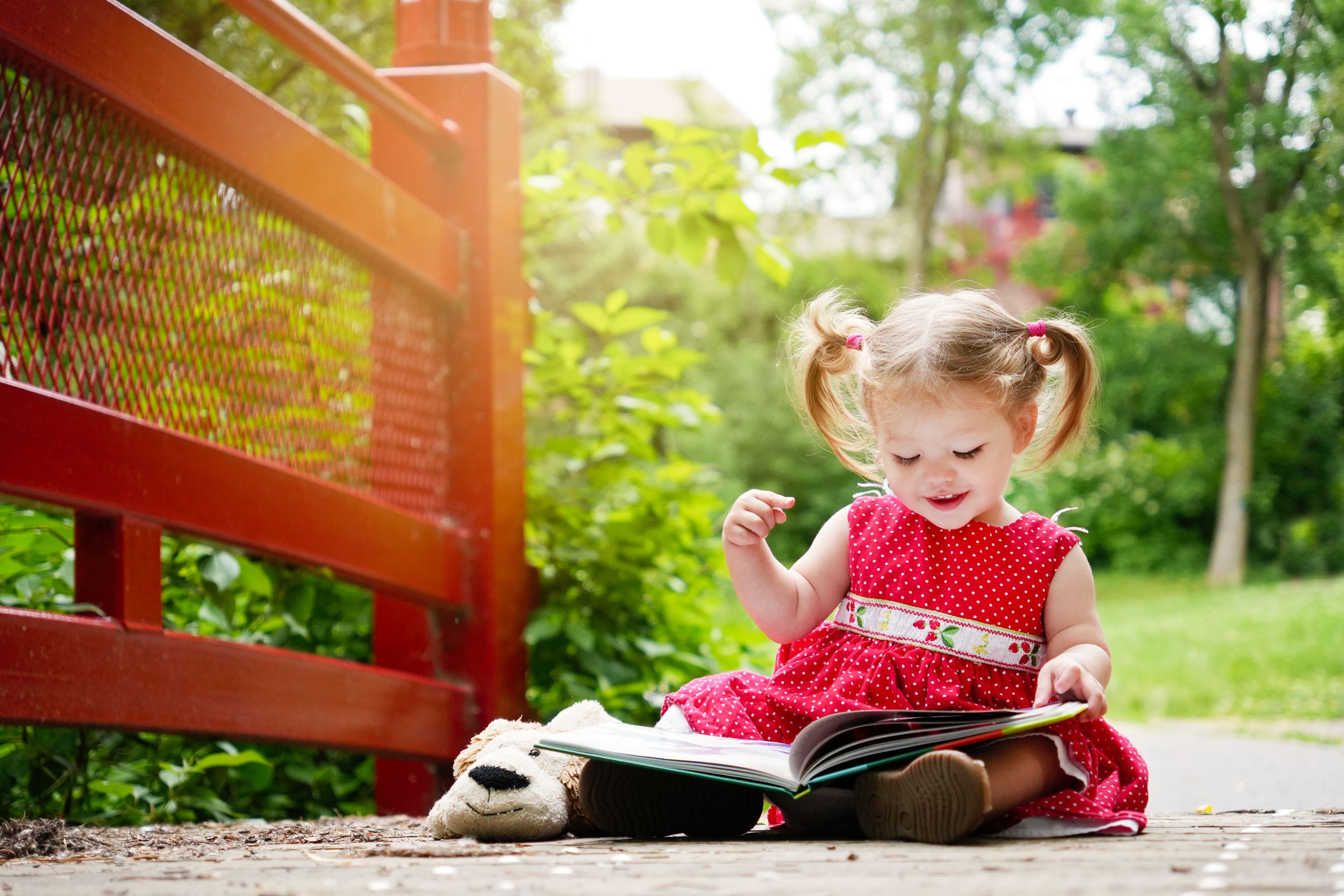 Photoshoot famille d'une magnifique petite fille qui lit un livre sur un pont avec la douce lumière du jour.