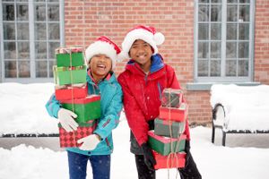 Seance famille de Noel avec de joyeux enfants qui portent des cadeaux colores dans le vieux La Prairie Quebec