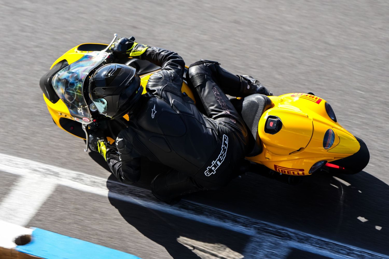 A yellow motorcycle racing at high speed on a racetrack.