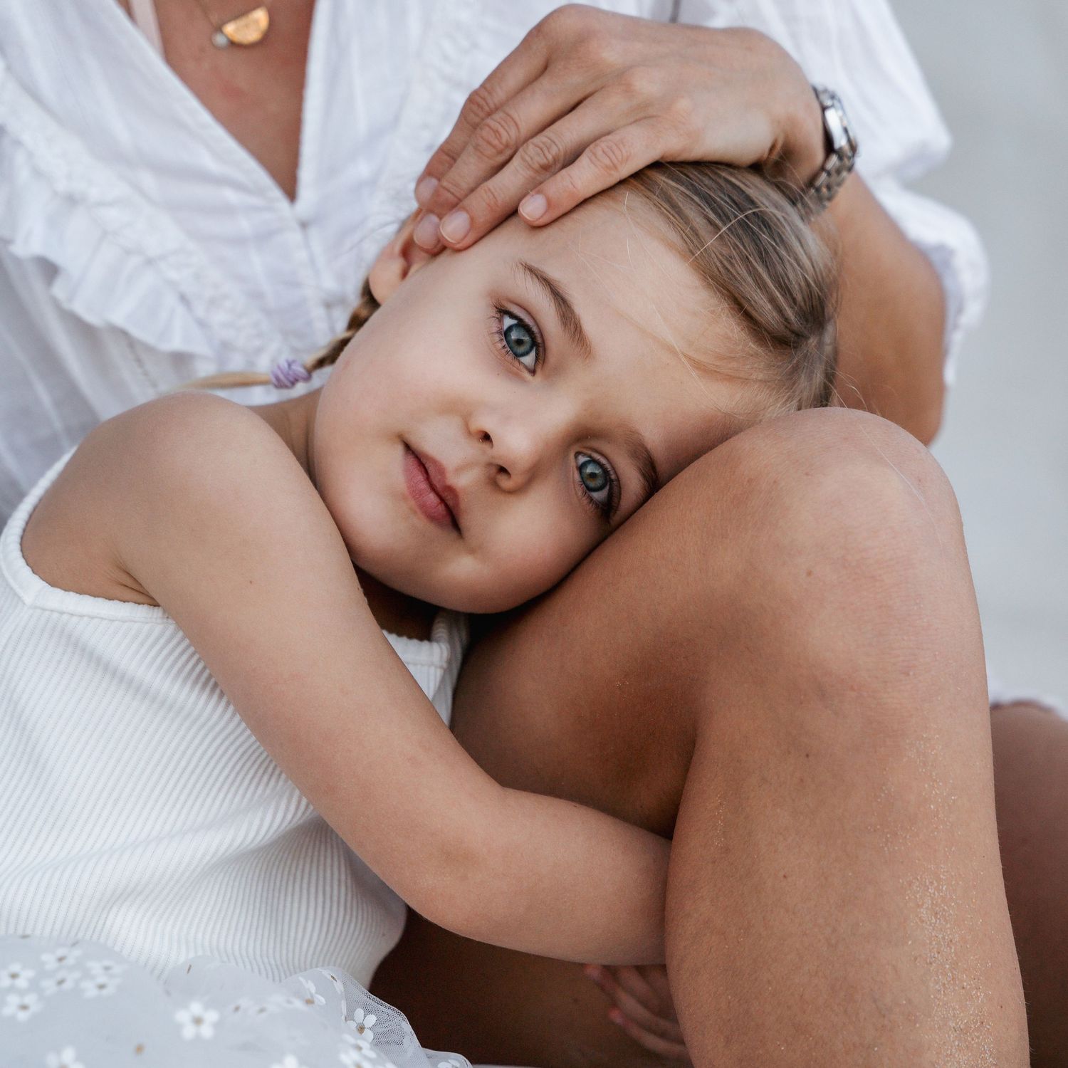close up photo of a blue eyed girl hugging her moms leg during a photoshoot