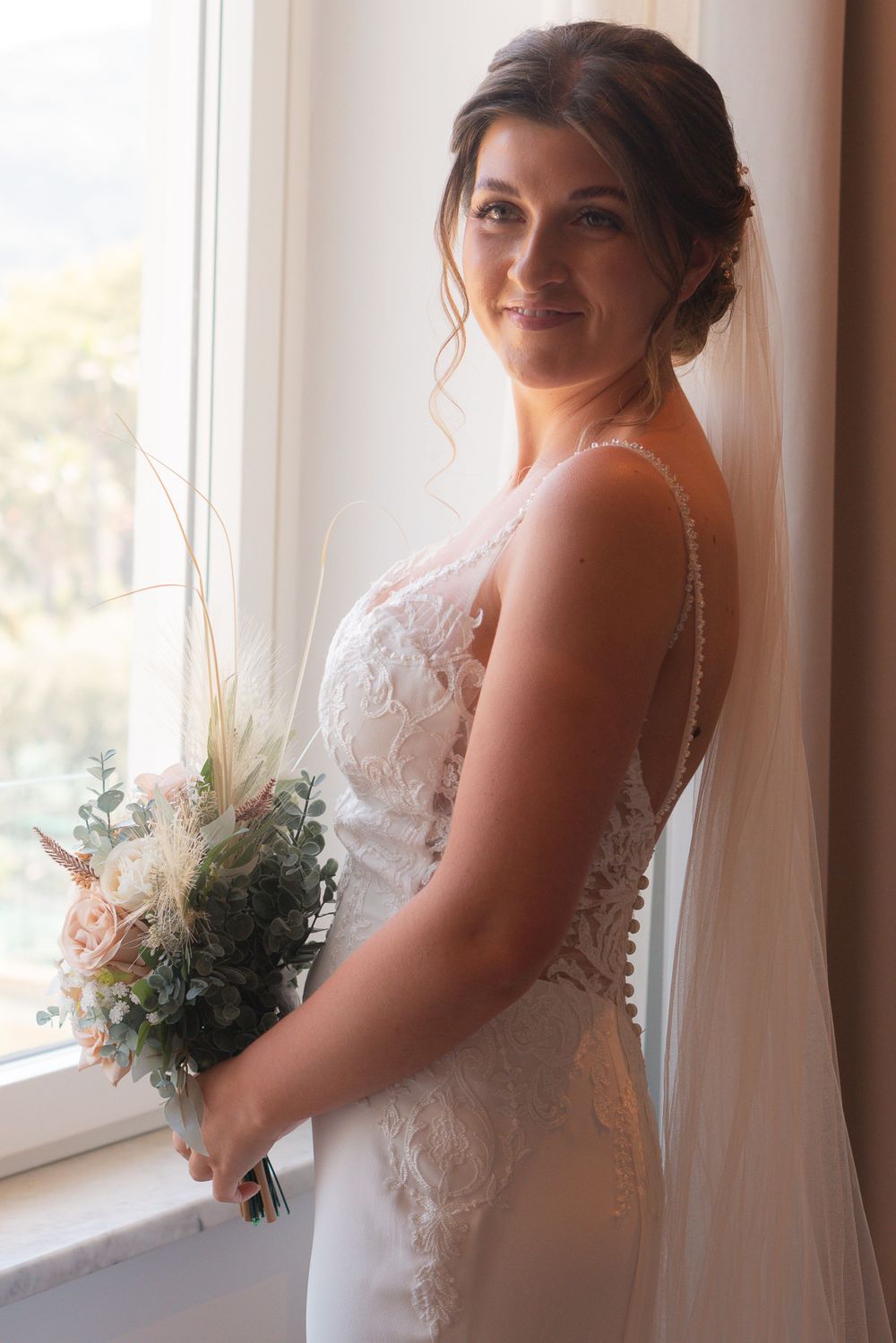 Bridal portrait of a bride looking over her shoulder, holding her wedding bouquet.