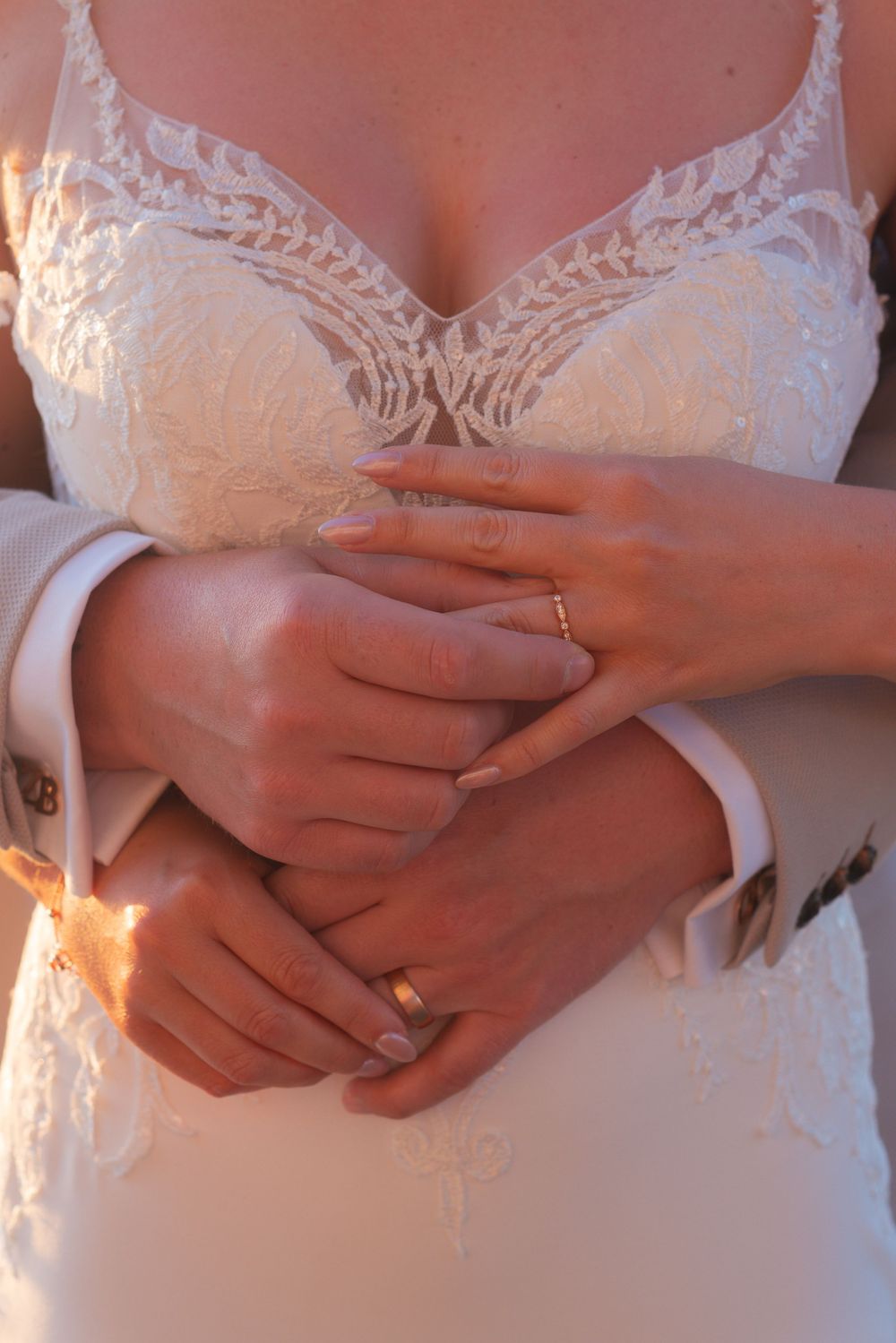 Intimate image, a close of up bride and grooms hands, they are holding onto each others new wedding bands.