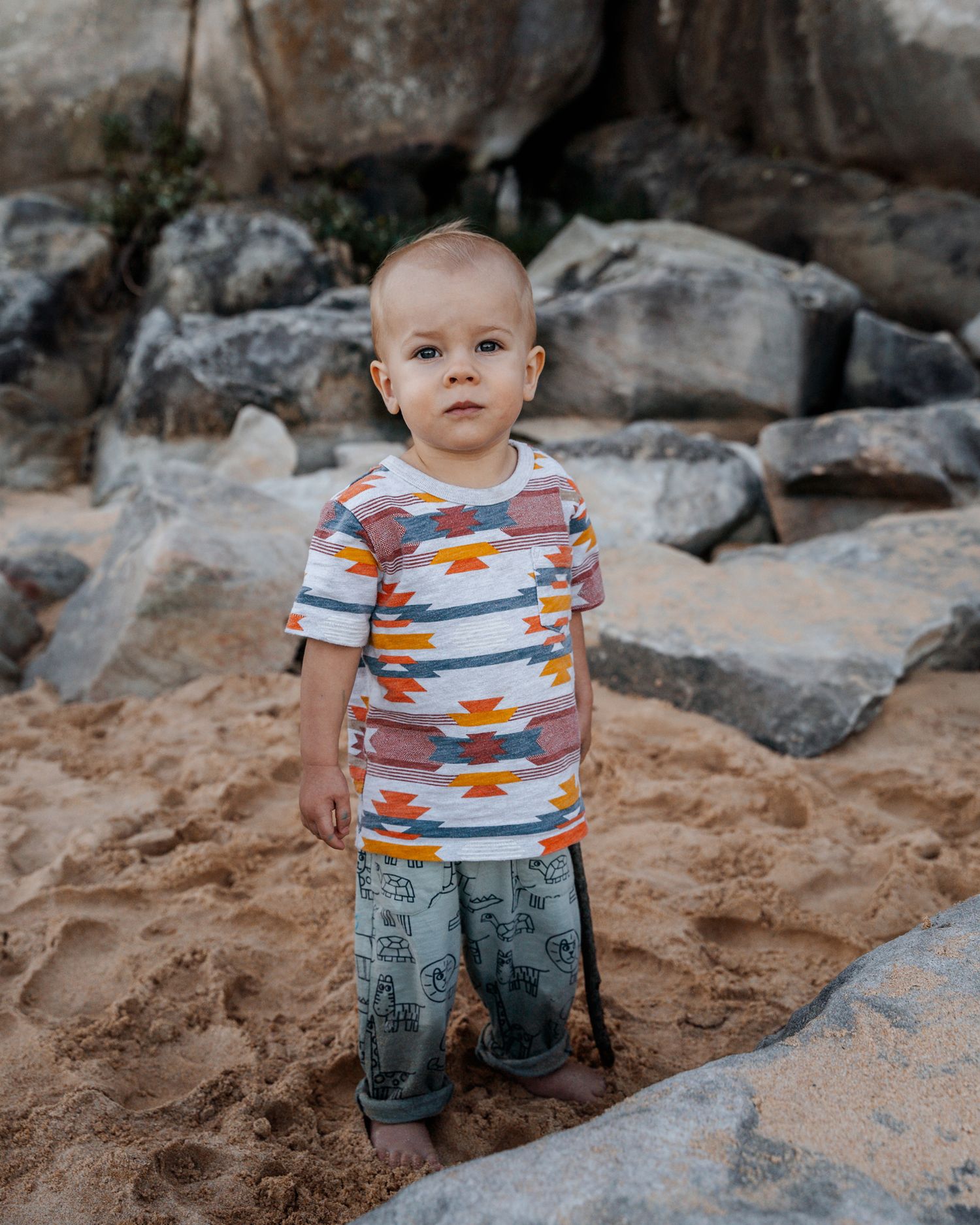 toddler exploring among the rocks in the sand at north curl curl northern beaches family photoshoot