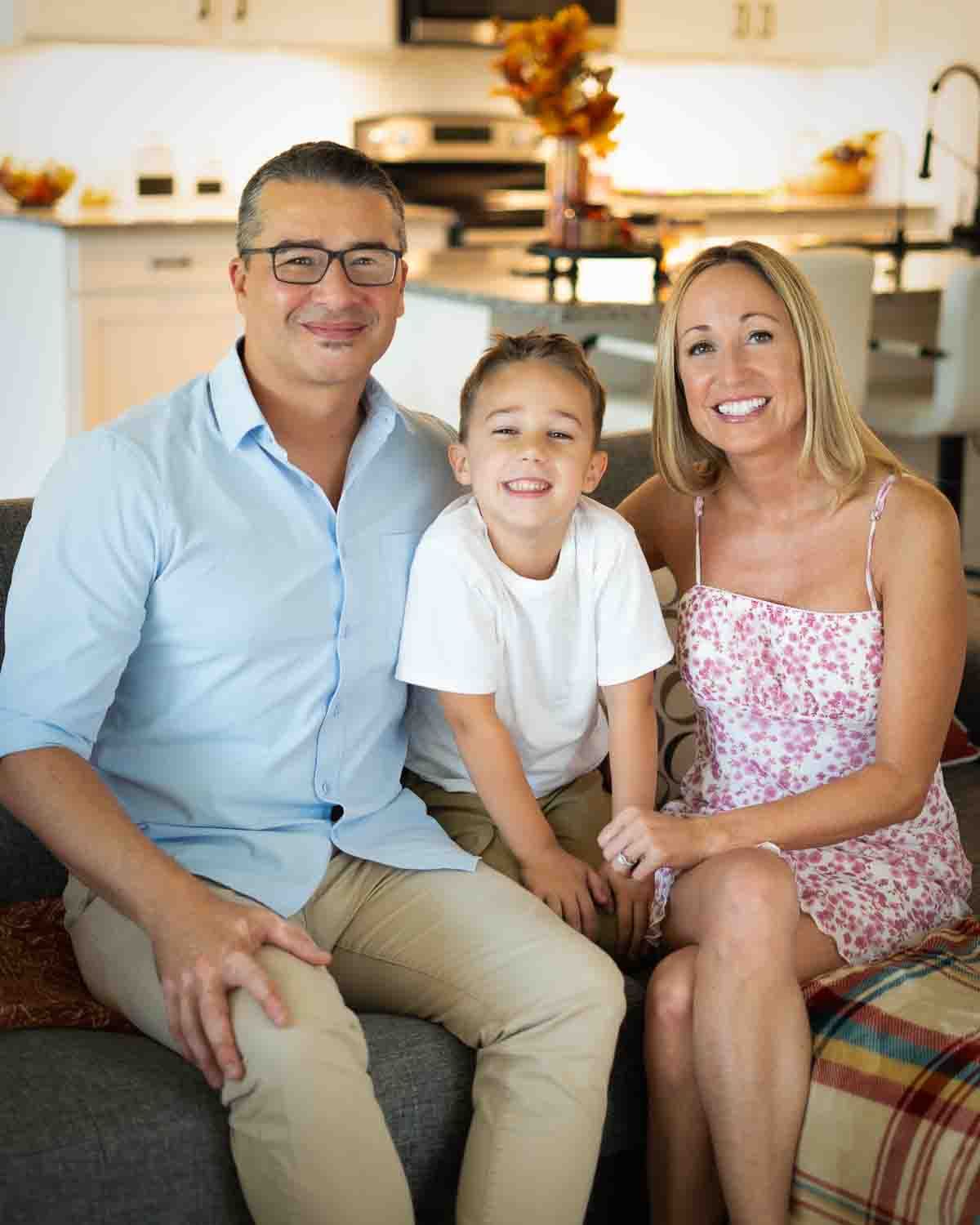 A casual indoor family portrait session on a couch showing joyful expressions and coordinated outfits.