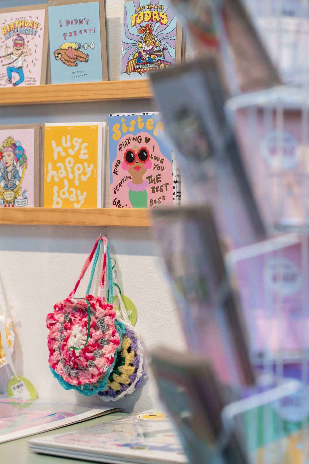 Colorful artwork and signage decorates a retail store wall with pink floral decorations hanging from the ceiling.