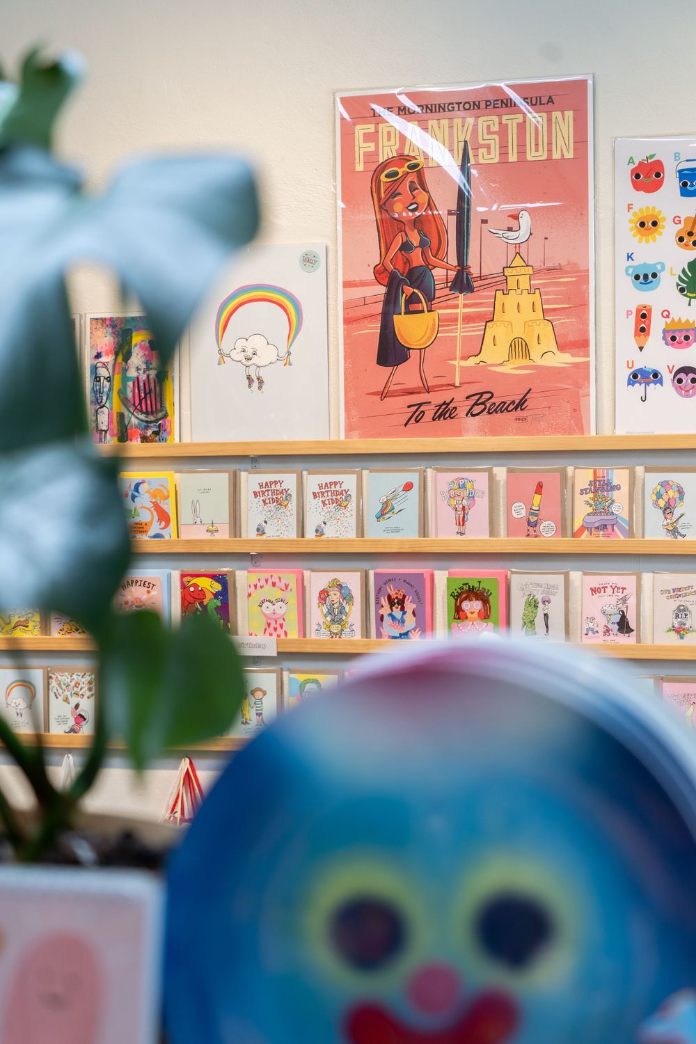Colorful art prints and illustrations displayed on shelves featuring whimsical cartoon characters.