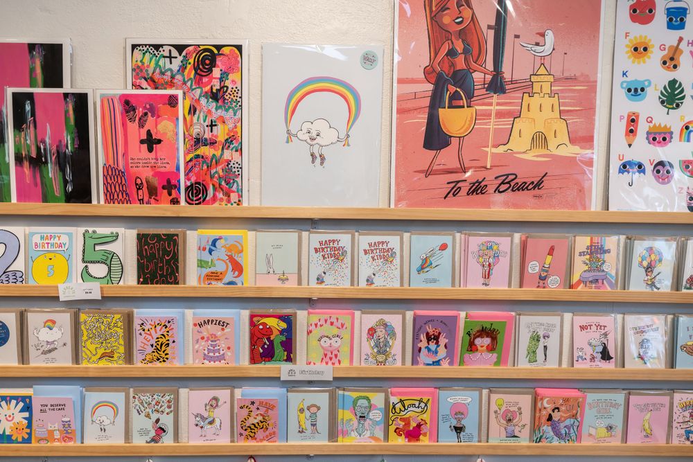 Wall display of colorful greeting cards and artwork featuring rainbows and illustrations.