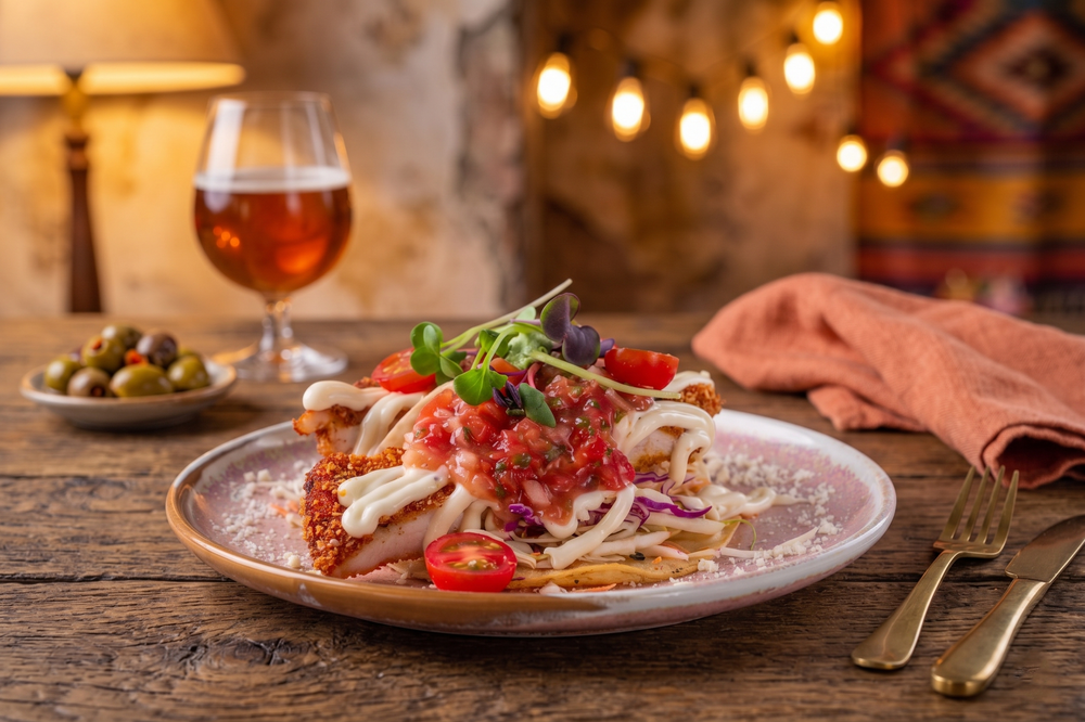 Gourmet seafood dish with tomato sauce, fresh herbs, and chili on a ceramic plate with wine glass.