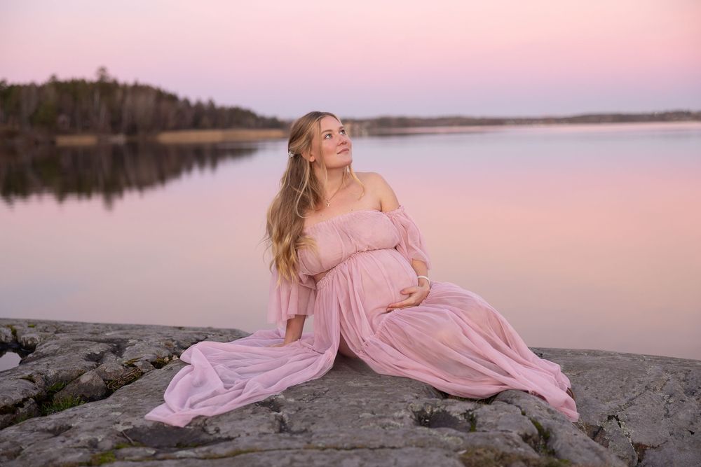 rosa solnedgångshimmel gravidfotografering med kvinna i rosa klänning