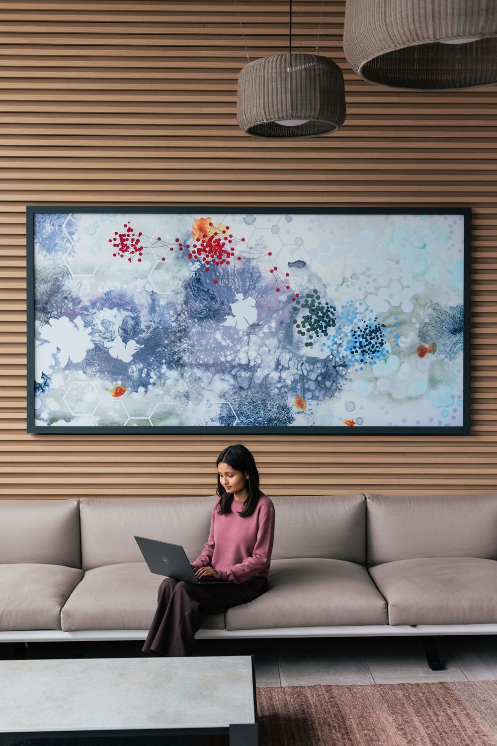 Modern office space with long wooden wall panels and abstract art featuring blue and white splatter designs.