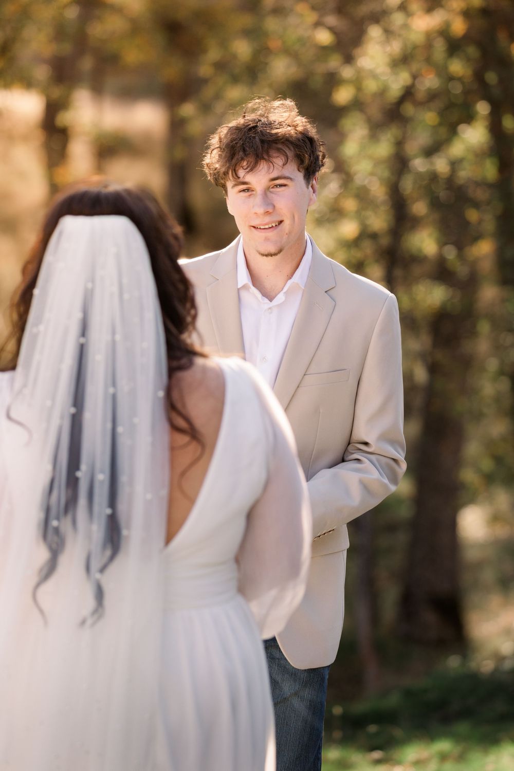 A joyful outdoor wedding photo shoot with a couple in white attire surrounded by autumn foliage.
