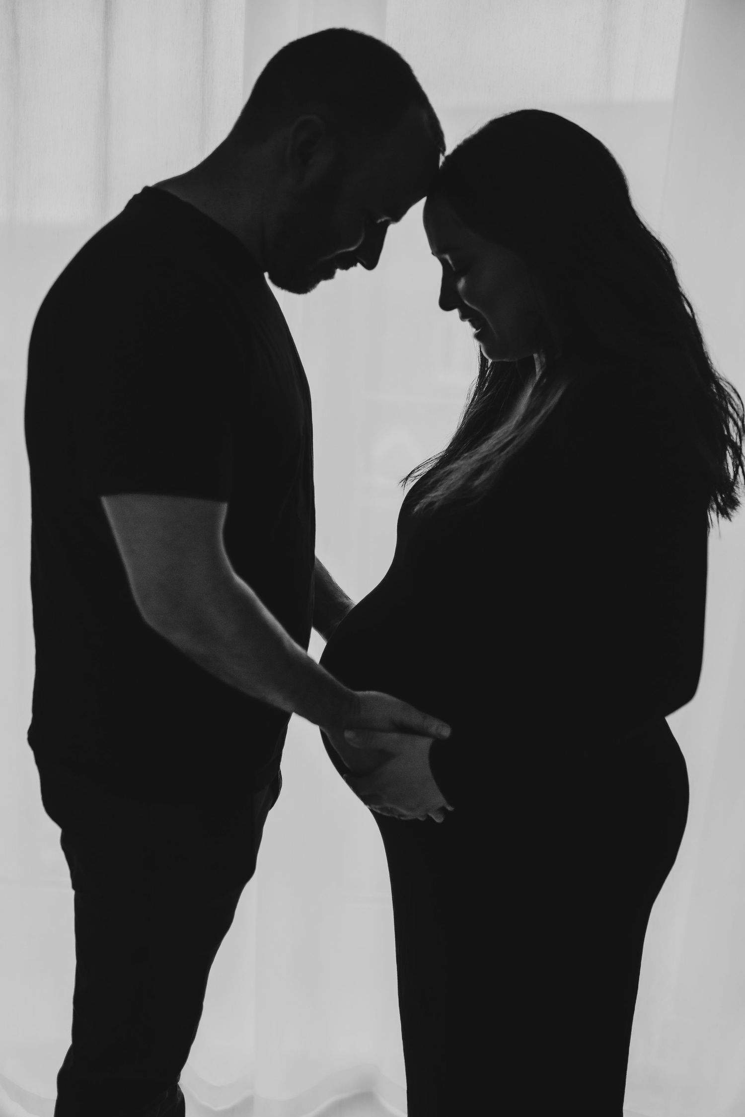 Black and white silhouettes of a couple showing progression of a pregnancy in artistic maternity photos.