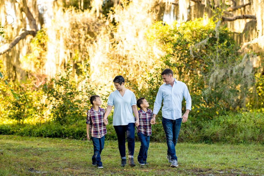 A group walks together through a sunlit park with Spanish moss hanging from trees in the background.