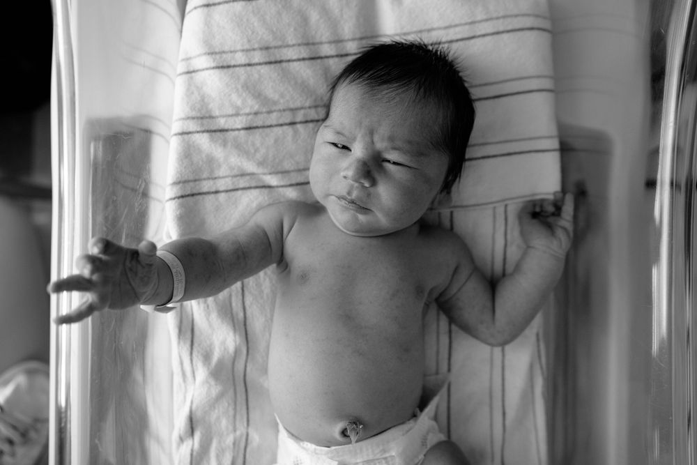 Medical professional examining a newborn baby in a hospital setting.