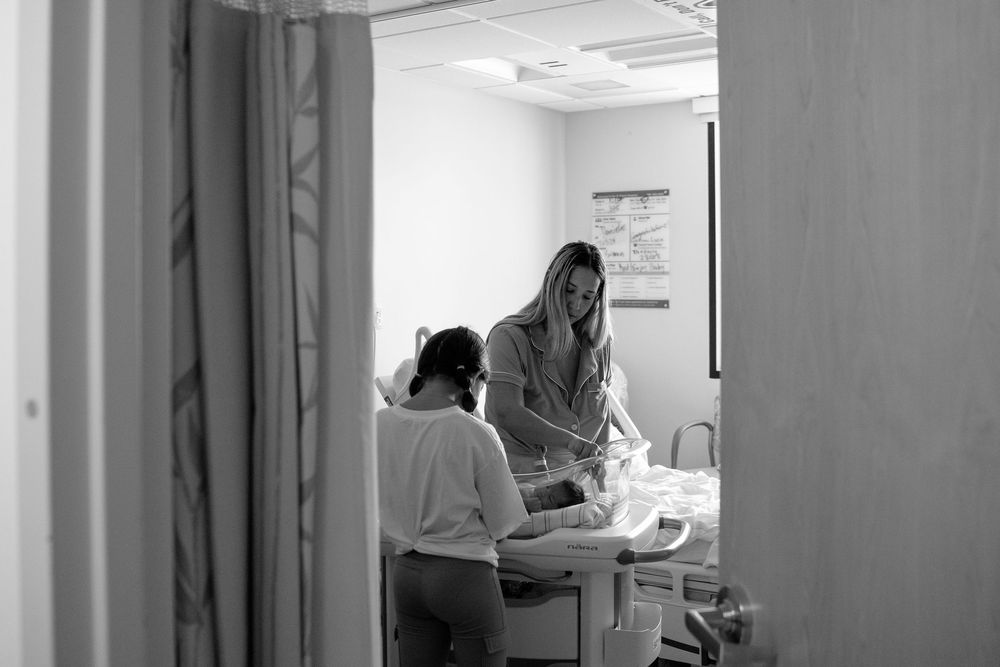 Black and white photo of medical staff in a hospital corridor reviewing patient charts and records.