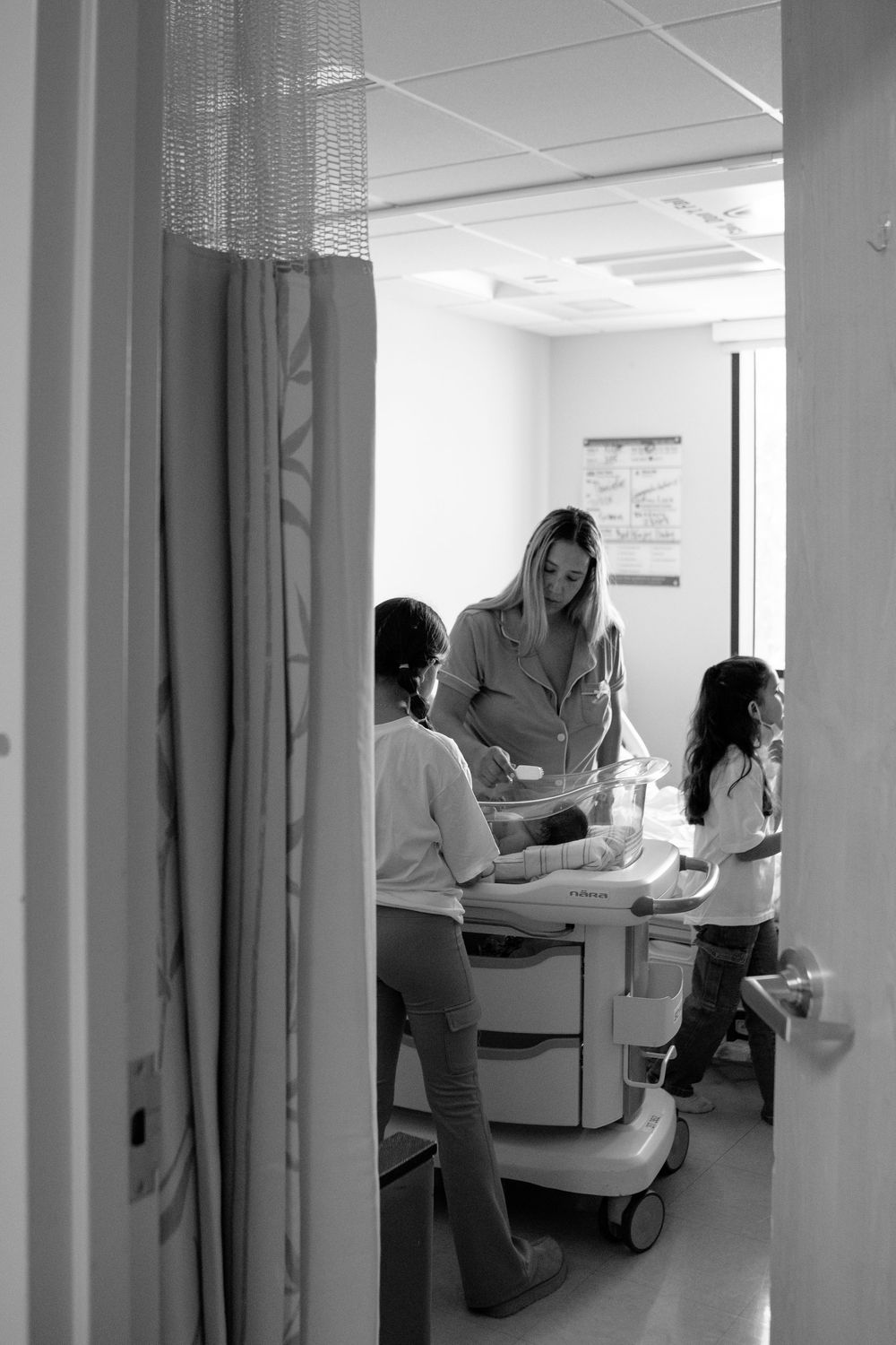Black and white sequence shows medical professionals working in a hospital hallway with equipment.
