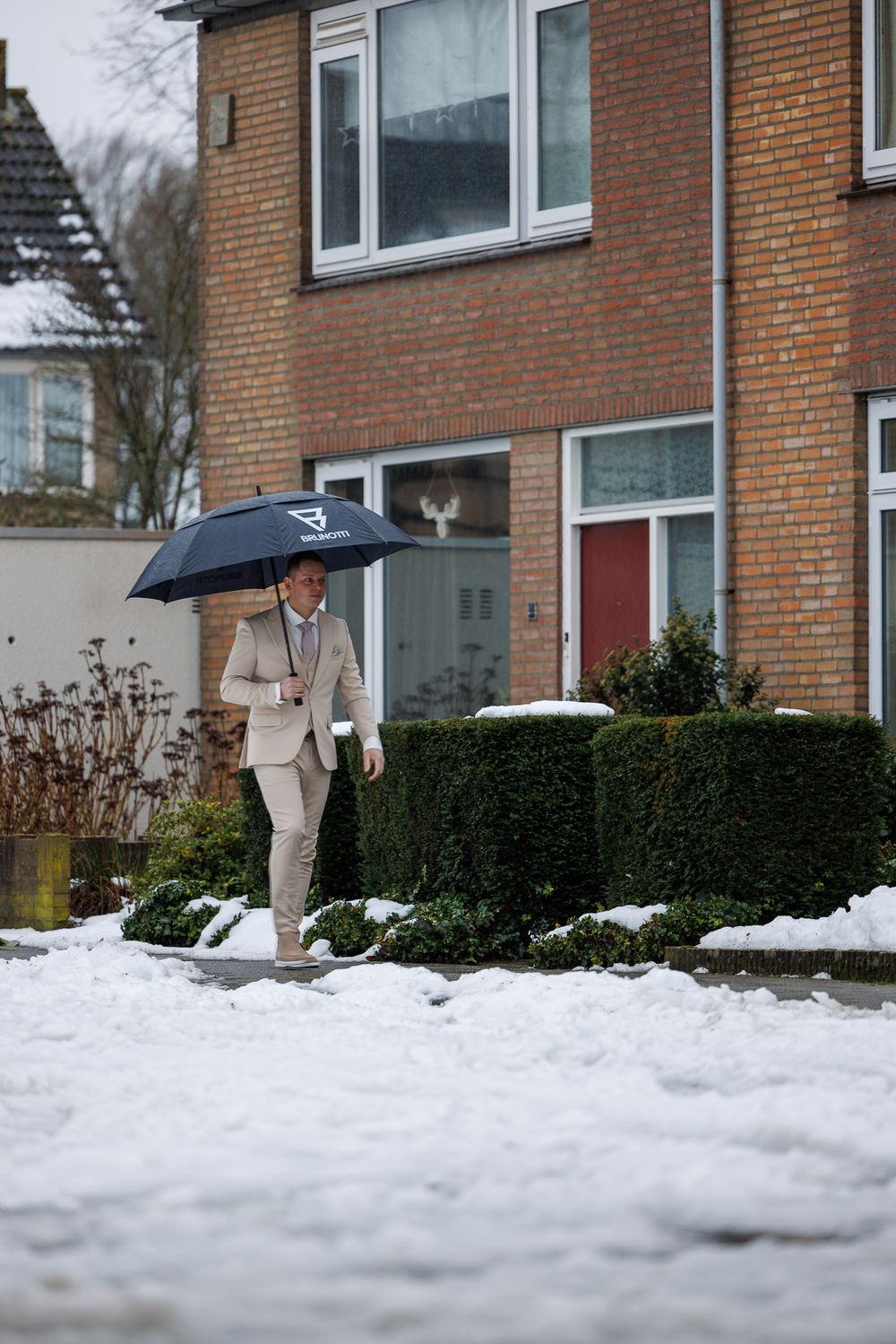 Bruidegom haalt bruid op onder paraplu op winterse dag met sneeuw - winter bruiloft - Drunen - MaxFotos
