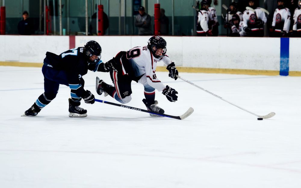 Palmyra Black Knights hockey player battling opponent for puck during game at York Ice Arena, York PA, by SportsFox Photography