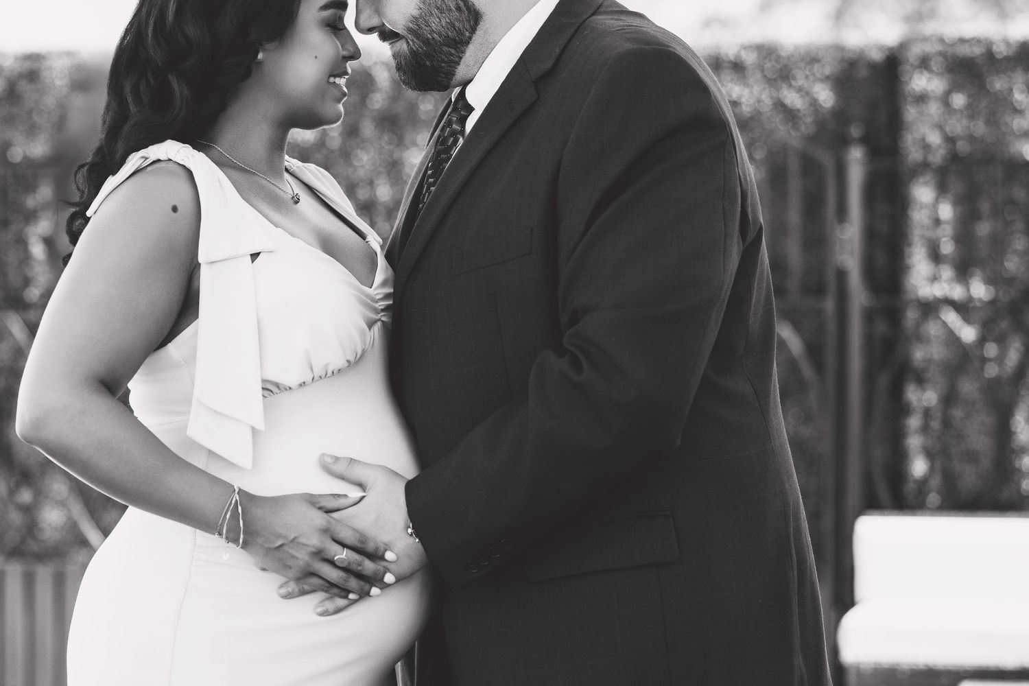 A black and white maternity photo showing a tender moment between an expectant couple.
