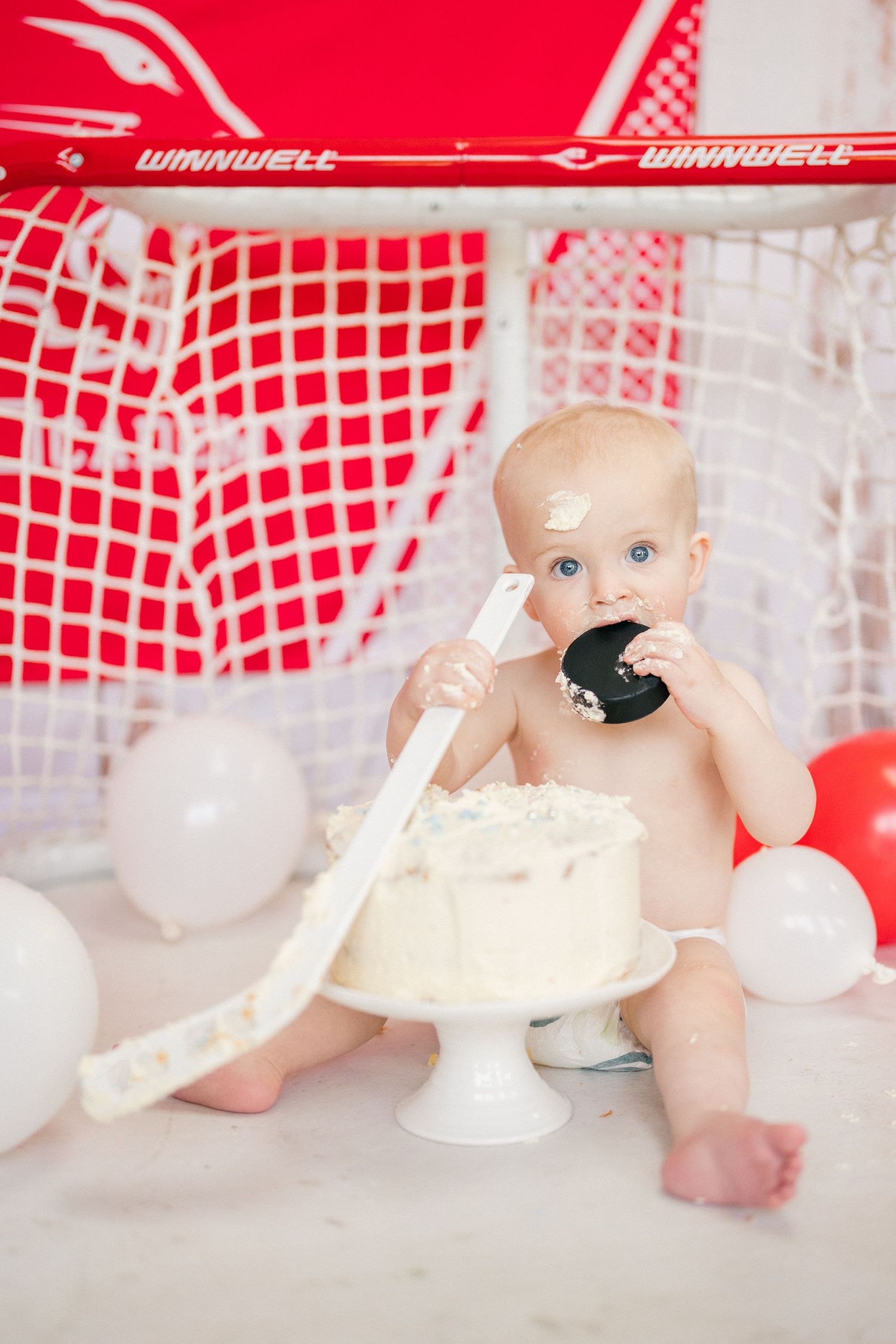 Natural family photography of a baby exploring a first birthday cake during a relaxed documentary family session