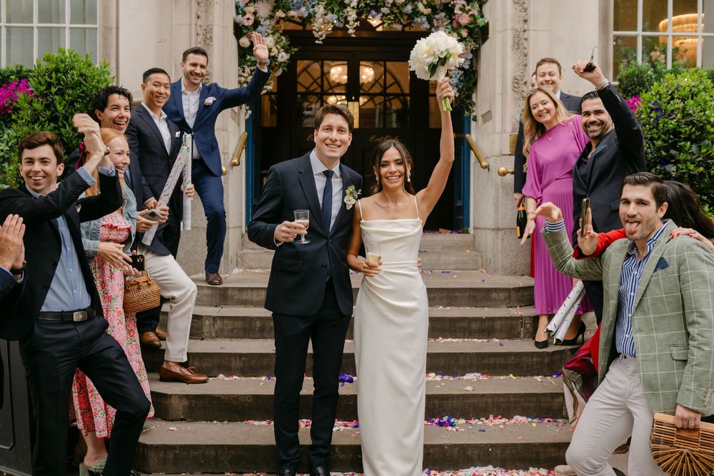 Wedding party and guests gather on stone steps for celebratory group photos.
