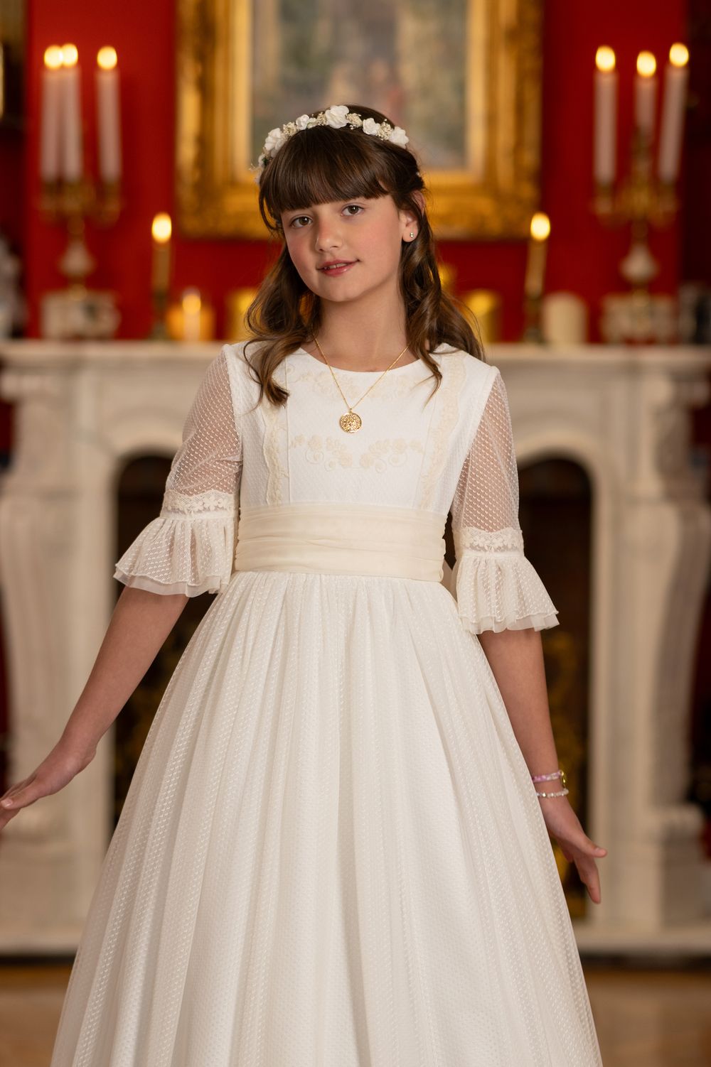 Young girl wearing an elegant white empire waist dress with puff sleeves in an ornate ballroom setting.