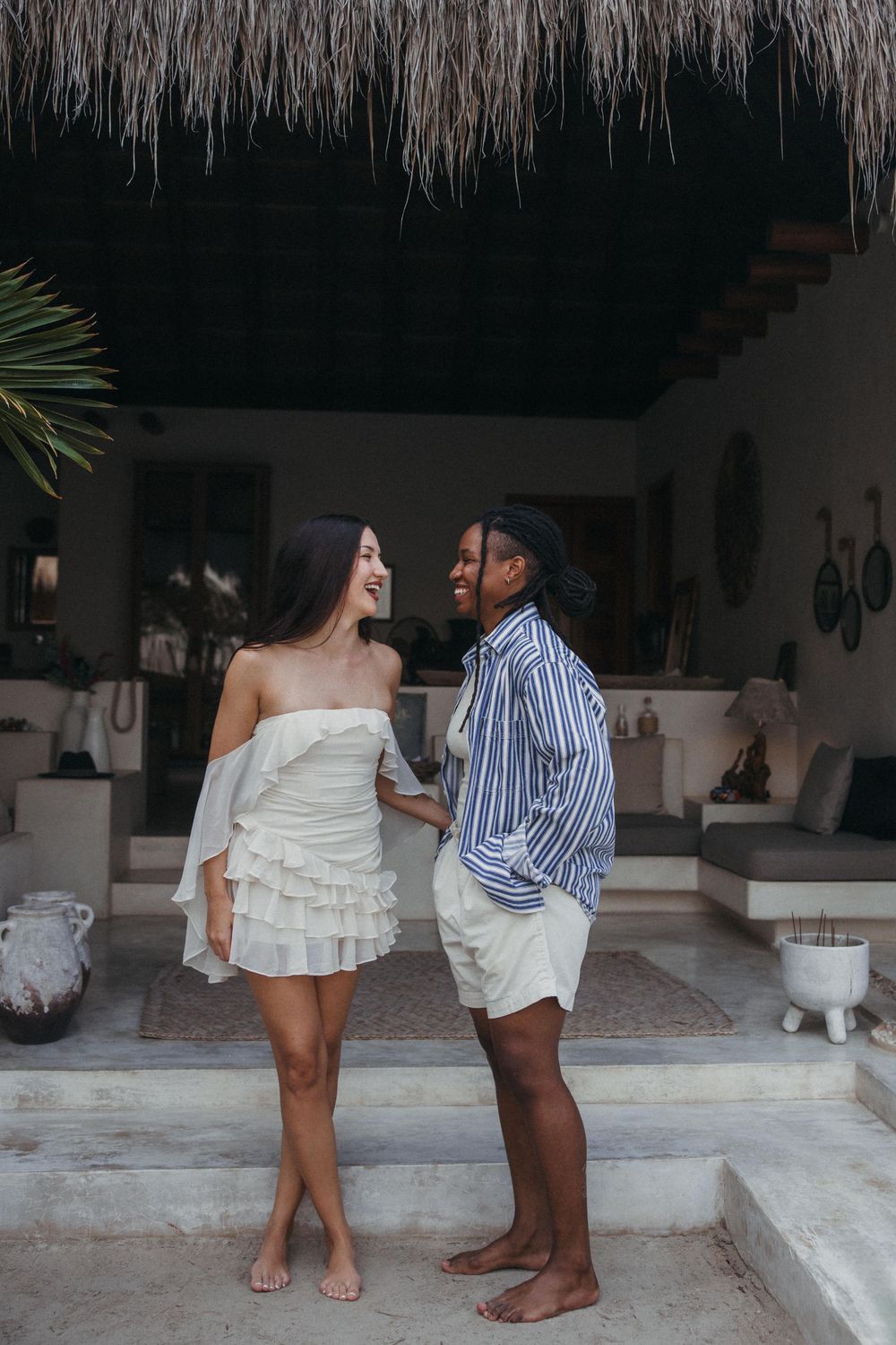 A gay couple during their photoshoot stands together in a tropical setting with palm trees at Tierra del Mar, Holbox Mexico