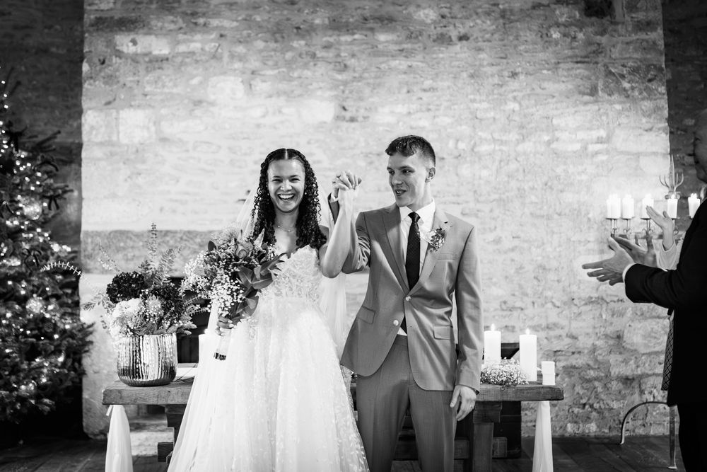 Black and white photo of a wedding celebration with guests gathered outside a historic stone church.