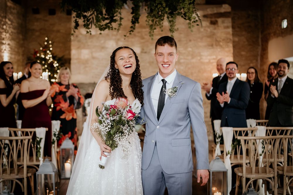 Joyful wedding celebration with guests in a rustic brick venue filled with natural light and greenery.