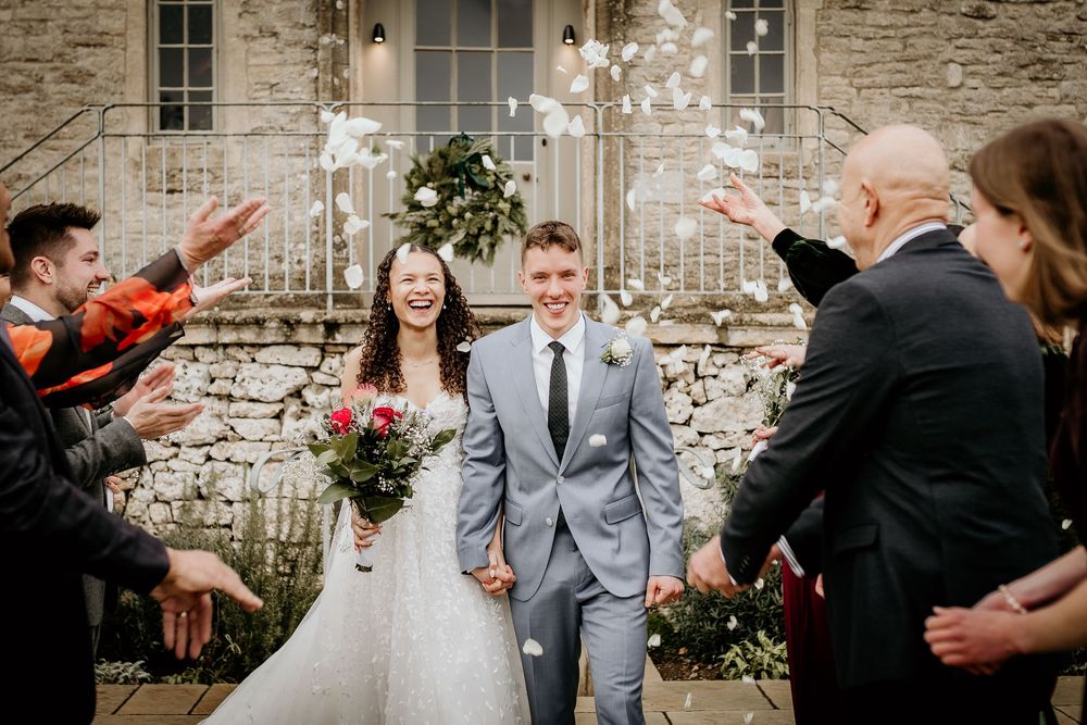 Wedding guests shower the newlyweds with sparklers outside a rustic stone building.
