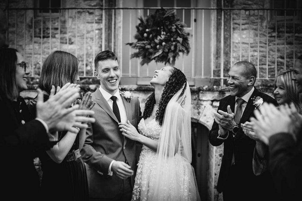 A group of wedding guests raise their glasses in celebration during an outdoor reception at dusk.