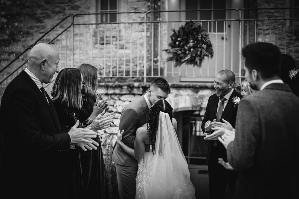 Black and white wedding photo series showing candid moments between guests and the couple during outdoor celebrations.