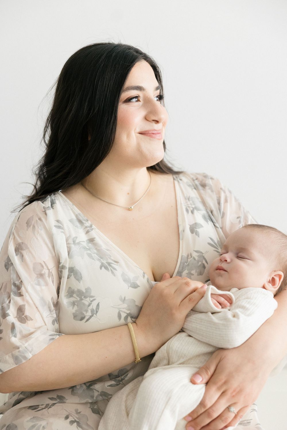 Soft portraits showing nurturing moments with a sleeping baby in a floral dress.