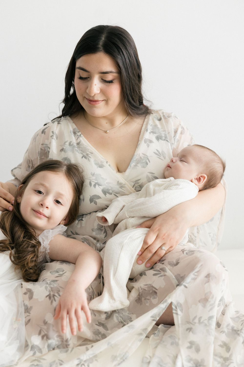 Sweet family moments captured in cream tones with siblings and a newborn.