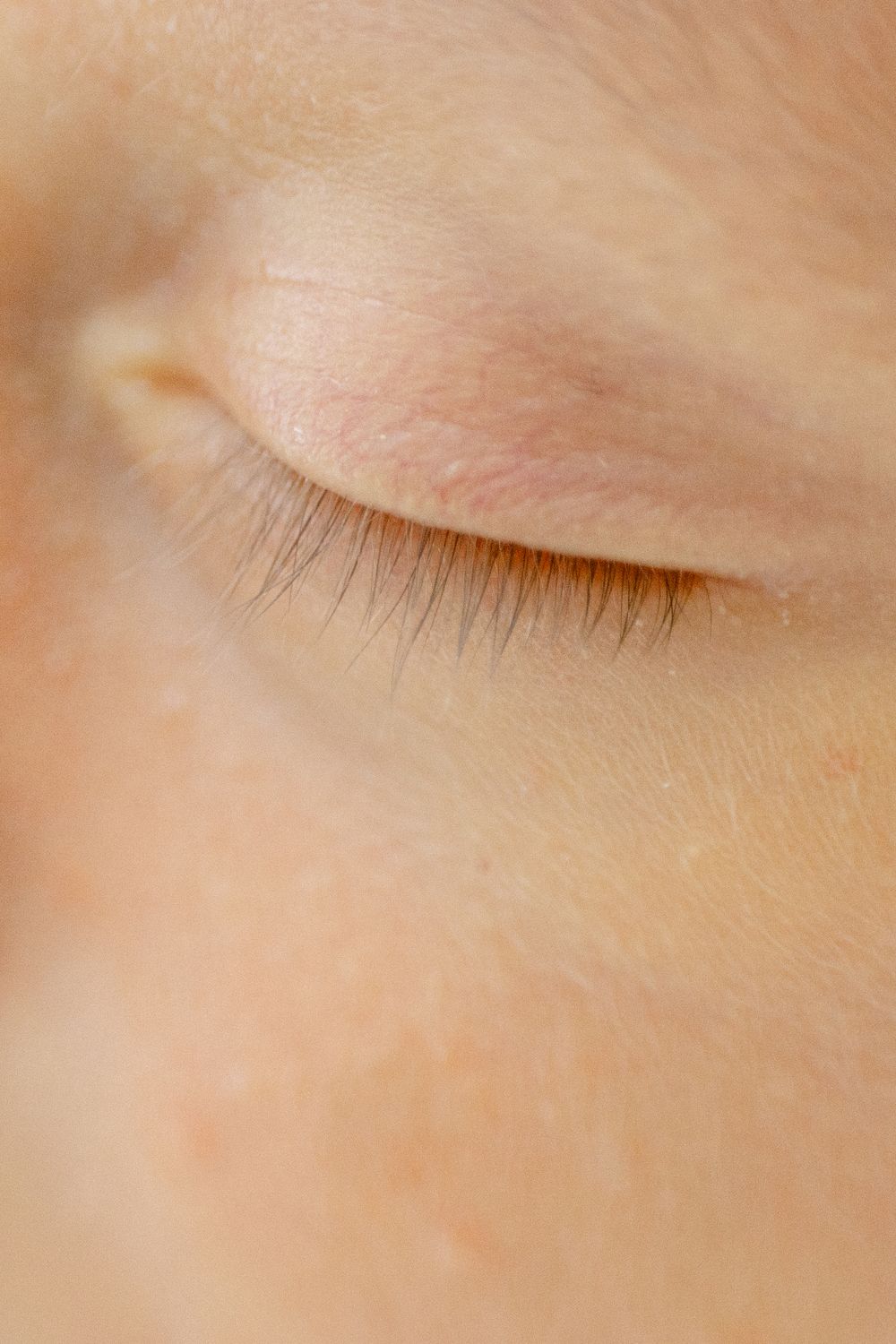Extreme close-up of delicate baby eyelashes and skin texture.