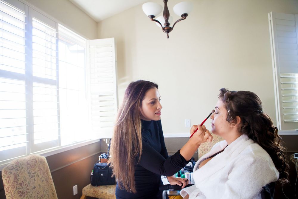 Professional makeup artist applies cosmetics to bride during wedding day preparation.