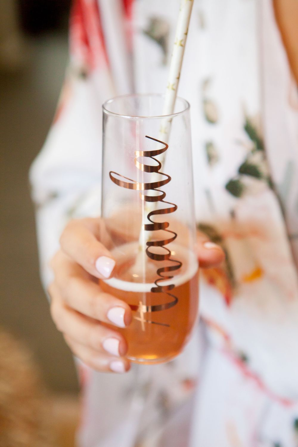 Close up of hands holding glass with amber liquid and spiral straw.