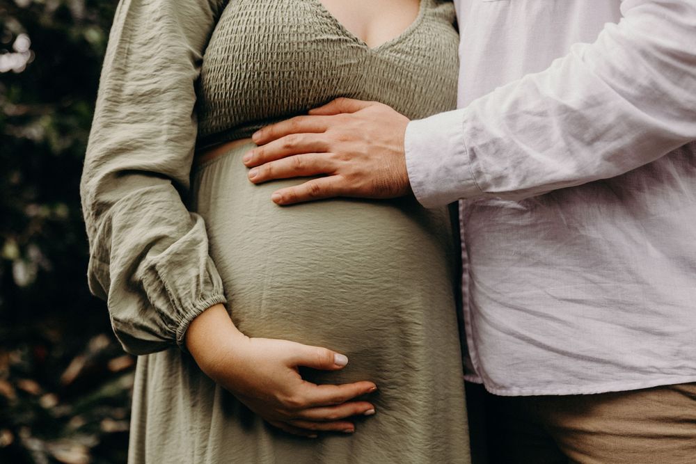 A series of photos showing gentle hands cradling a pregnant belly in an outdoor maternity photoshoot.
