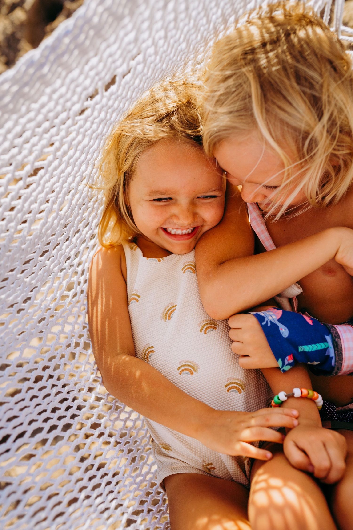 kaanapali family photography. Sweet candid moment between two children relaxing in hammock with dappled sunlight.